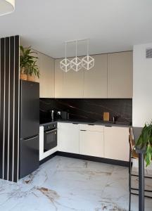 a kitchen with white cabinets and black appliances at Apartament nad Wartą Śrem in Śrem