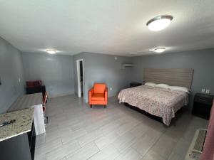 a bedroom with a bed and an orange chair at Apollo Inn - Downtown in Kissimmee +2 photos