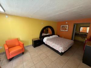 a bedroom with a bed and an orange chair at Apollo Inn - Downtown in Kissimmee
