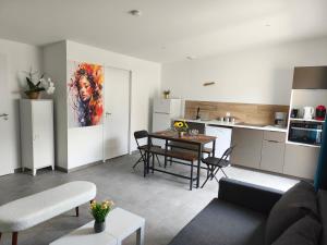 a living room with a table and a kitchen at Gîtes Néphélie votre cocon tout confort aux portes du Puy duFou - Climatisé, Terrasse, Parking in Les Épesses
