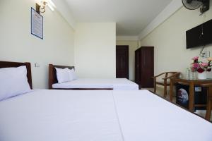 two beds in a hotel room with white sheets at Loan Ngạn Hotel Hải Hòa in Nghi Sơn