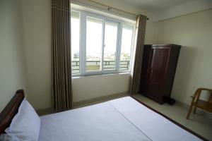 a bedroom with a bed and a large window at Loan Ngạn Hotel Hải Hòa in Nghi Sơn