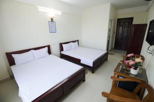 a bedroom with two beds and a table with flowers at Loan Ngạn Hotel Hải Hòa in Nghi Sơn