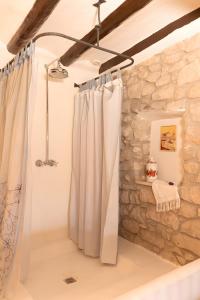 a shower curtain in a bathroom with a stone wall at La Festa Dels Sentits, Casa Rural in Sant Martí de Maldá