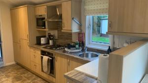 a kitchen with wooden cabinets and a sink and a window at Ednas Lodge in Wisbech
