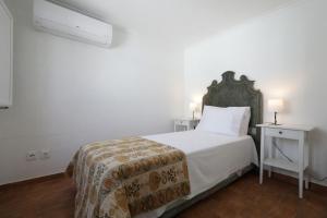 a white bedroom with a bed and two night stands at Casa Tradicional Algarvia in Tavira