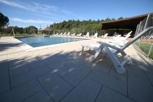 a group of chairs sitting around a swimming pool at Il Vignone - Castagneto Carducci in Castagneto Carducci