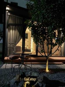 a table and chairs and a tree in front of a house at LuxEcoCottage in Podgorica