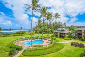 an aerial view of a resort with a swimming pool and palm trees at Kaha Lani 212 - Oceanfront 2BR Condo with Pool, Tennis & BBQs in Wailua