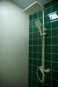 a green tiled bathroom with a shower with a shower head at Yunxi Courtyard in Zhangzhou