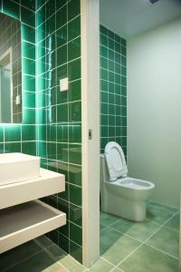 a green tiled bathroom with a toilet and a sink at Yunxi Courtyard in Zhangzhou