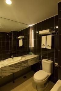 y baño con aseo y lavamanos. en Hotel Anika Kluang en Kluang