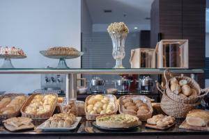 a display case with various types of bread and pastries at Hotel Açores Premium- 5 minutos do Moinhos de Vento in Porto Alegre