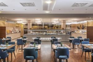 a restaurant with tables and chairs and a kitchen at NH Vienna Airport Conference Center in Schwechat