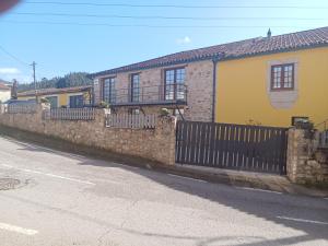 a stone fence in front of a yellow house at DF Alojamentos e suites in Coimbra
