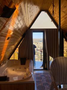 eine Badewanne in einem Raum mit einem großen Fenster in der Unterkunft أكواخ المها oryx cottage in Adschlun + 19 Fotos