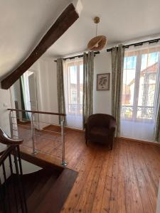 a living room with wooden floors and windows and a chair at La Crécynade - near Disneyland and Parrot World in Crecy la Chapelle