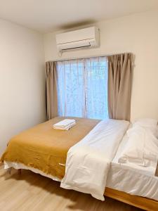 a bedroom with a bed and a window with a air conditioner at THE ONE kouennji in Tokyo