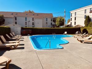 a swimming pool with chaises and chairs in a courtyard at Lumineux condo au bord du lac in Magog-Orford