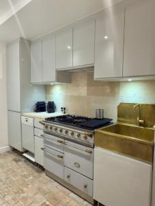 a kitchen with white cabinets and a stove and a sink at L'écrin de la Chartreuse in Villeneuve-lès-Avignon