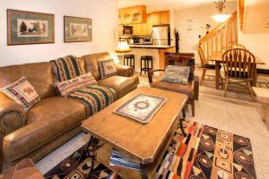 a living room with a brown couch and a table at Chamonix Year-Round Fun with Shared Pool in Mammoth Lakes
