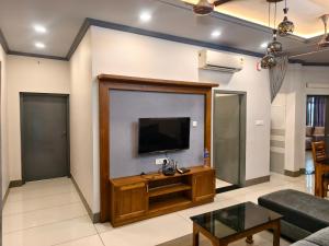 Una sala de estar con un televisor de pantalla plana en una pared. en Kovoor residency, en Thiruvalla