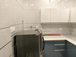 Una cocina con gabinetes blancos y un refrigerador. en Kovoor residency, en Thiruvalla
