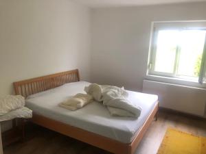 a small bed with white sheets and a window at VeWö Seeklang in Velden am Wörthersee