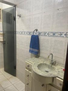 a bathroom with a sink and a shower with a blue towel at Casa tamanho Família Aconchegante in Bauru