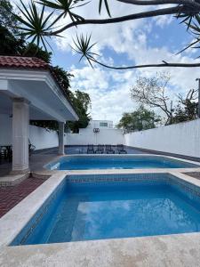 a swimming pool next to a white wall at Alojamiento para 6 personas con piscina in Chuburná de Hidalgo