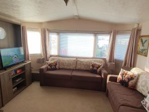 a living room with a couch and a flat screen tv at Hayling Island Caravan in Hayling Island