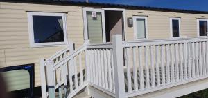 a house with a white fence and a porch at Hayling Island Caravan in Hayling Island +2 photos