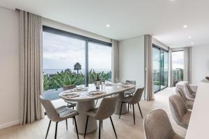 a dining room with a table and chairs and a large window at Eco Fajã Villas in Arco da Calheta