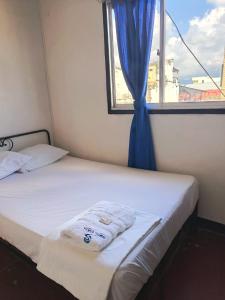 a bed with a blue curtain and a window at Hotel Efata in Apartadó