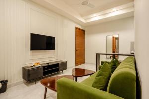 a living room with a green couch and a television at Royal Studio Golf Course Road in Gurgaon