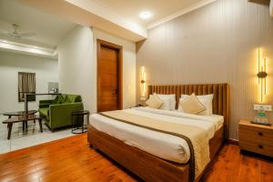 a bedroom with a large bed and a green chair at Royal Studio Golf Course Road in Gurgaon