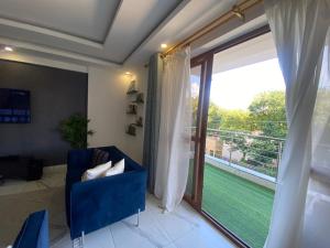 a living room with a blue chair and a large window at Breeze Apartment in Mombasa