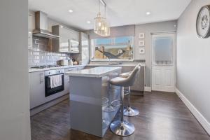 a kitchen with a sink and a bar stool at The Beach House - North East Escapes in Whitley Bay