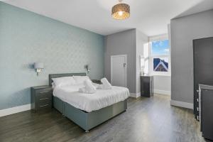 a bedroom with a bed and a blue wall at The Beach House - North East Escapes in Whitley Bay
