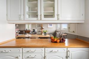 a kitchen with white cabinets and a bowl of fruit on a counter at Tomasjord home, the top floor in Trondalen +16 photos