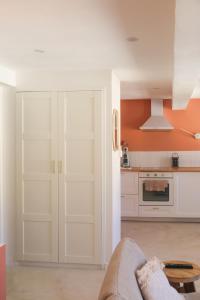 a kitchen with white cabinets and an orange wall at Magnifique Studio moderne in Pierrefeu-du-Var +14 photos