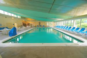 a large swimming pool with blue chairs in a building at Sea Mist Resort in Mashpee