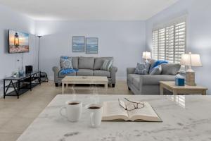 a living room with a book and glasses on a table at Renovated 2-Bedroom Condo with Pool - The Waves in St. Pete Beach