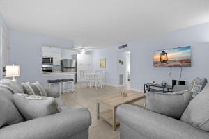 a living room with two couches and a kitchen at Renovated 2-Bedroom Condo with Pool - The Waves in St. Pete Beach