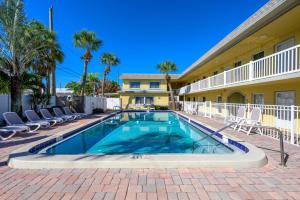 a swimming pool in front of a building with chairs at Renovated 2-Bedroom Condo with Pool - The Waves in St. Pete Beach