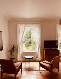 a living room with a window and a table and chairs at The Arches, Georgian Apartment in Cobh