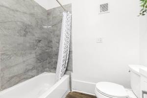 a bathroom with a white tub and a toilet at Cozy Inn Holbrook NorthEnd in Hamtramck +14 photos