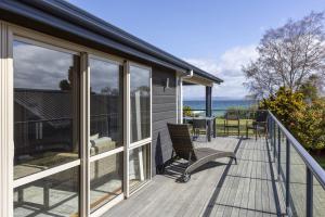 a house with a balcony with a view of the ocean at Still Water Retreat - beautiful lake front location and living in Waitahanui