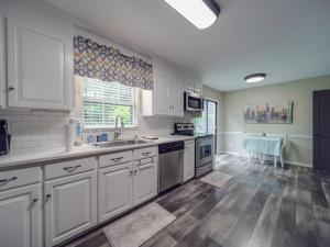 a large kitchen with white cabinets and a hardwood floor at 4 BR South Charlotte Getaway Min to Everything in Charlotte