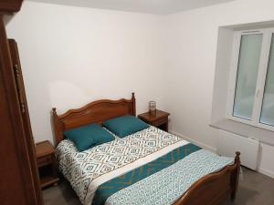 a bed with two blue pillows in a bedroom at Appartement 3 chambre 4 lits doubles dans les Gorges de la Sioule proche rivière in Menat